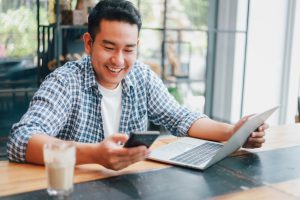 Asian young man in blue shirt working with laptop computer and m