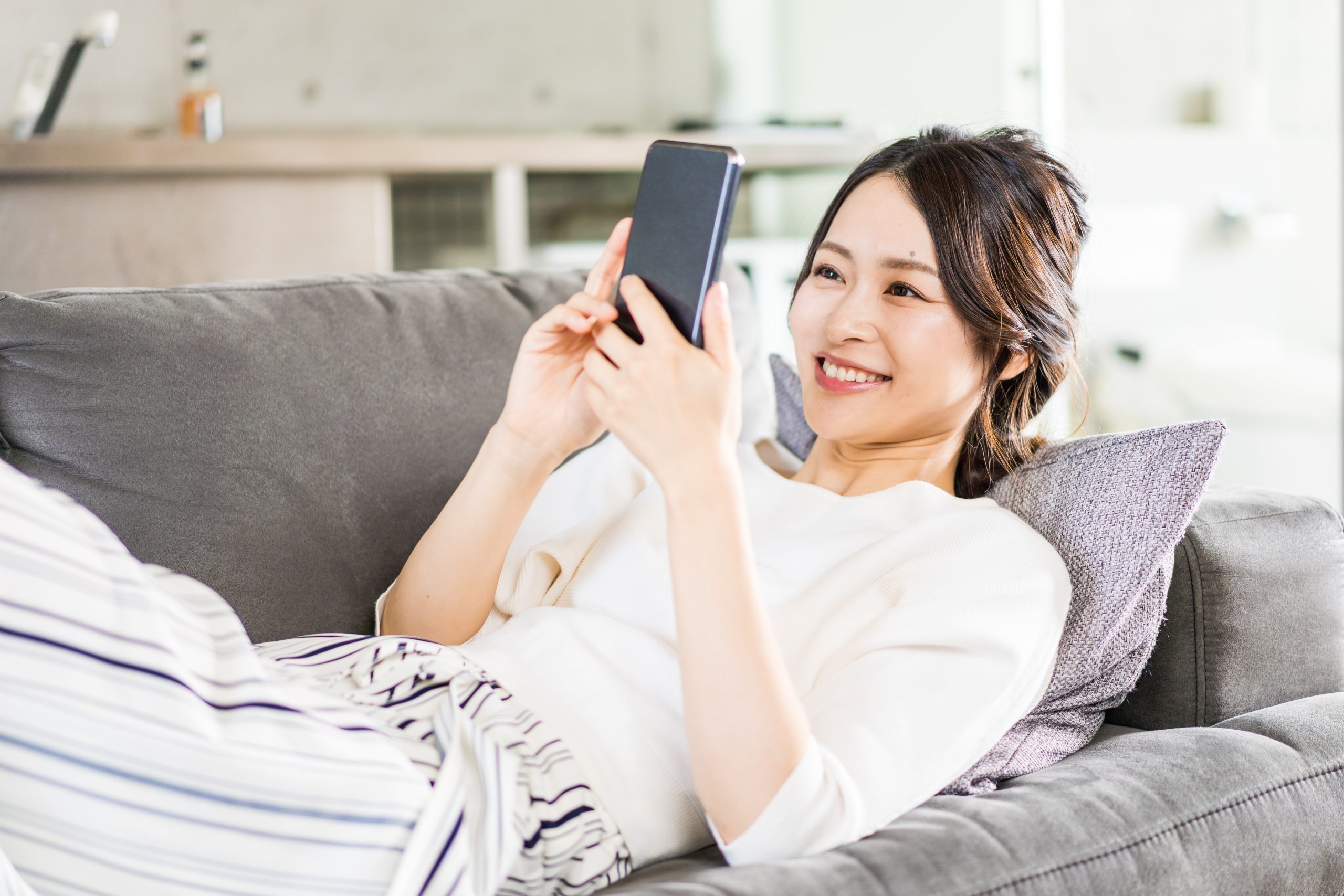 部屋でスマホを使う若い女性