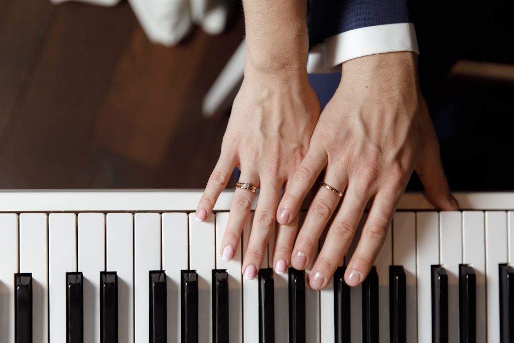 Groom and and bride hands with rings. On piano, close up