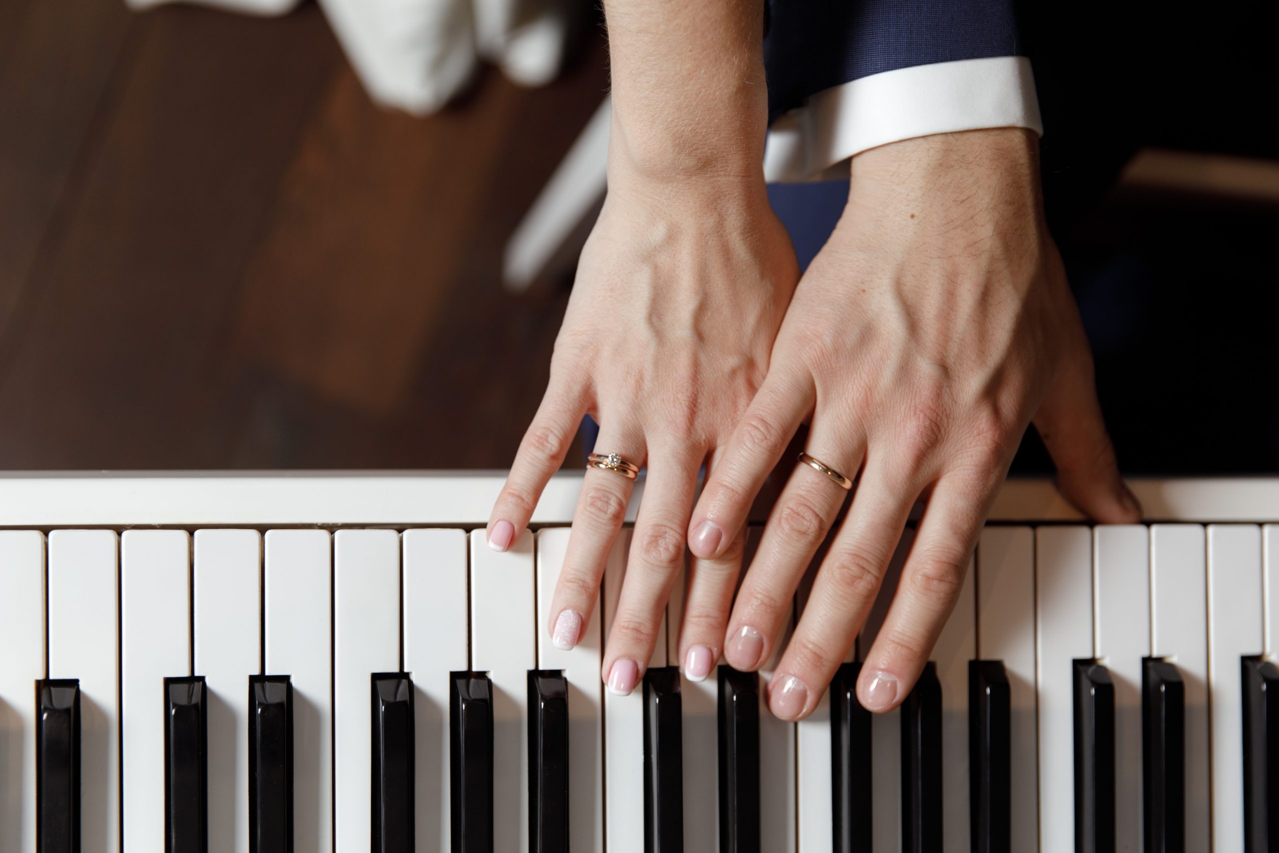 Groom and and bride hands with rings. On piano, close up